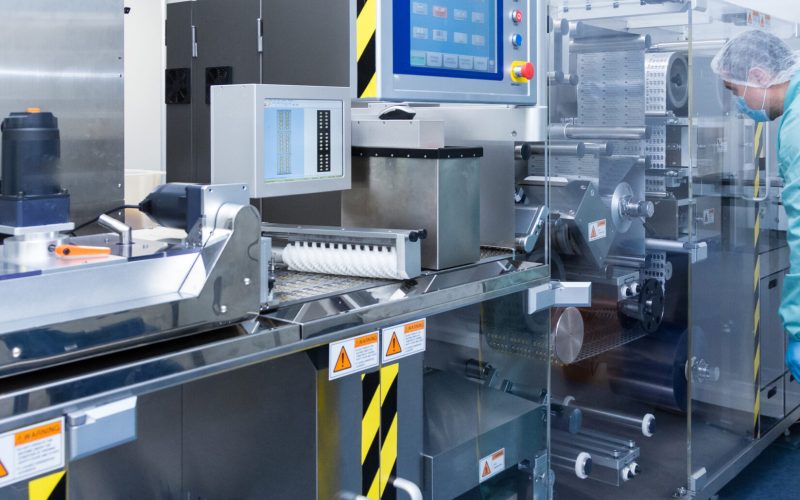 Pharmaceutical technician in sterile environment working with equipment at pharmaceutical manufacturing